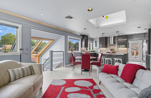 Hough Apartment | Top-level duplex featuring a sleek open concept kitchen with stainless appliances, cozy fireplace, stylish furnishings, and in-unit washer/dryer. Designed for basking in the sun under skylights in thoughtful details throughout.